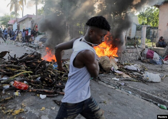 Yon gason kouri bo kote yon barikad kap boule pandan yon manifestasyon kont gouvenman an ak ogmantasyon pri petwol la nan Potoprens, Ayiti, 3 Oktob, 2022.