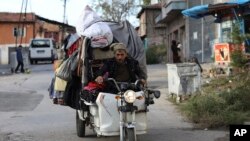 Seorang pria penjual pakaian murah mengendarai sepeda di distrik Ulus, bagian lama ibu kota Turki, Ankara, Turki, Minggu, 23 Oktober 2022. (AP/Burhan Ozbilici)