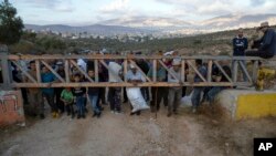 Palestinian farmers wait behind an Israeli army security gate to be permitted on to their lands to harvest olives, in the West Bank village of Salem, east of Nablus.