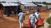 Health workers walk outside the Ebola isolation section of Mubende Regional Referral Hospital, in Mubende, Uganda, Sept. 29, 2022. 