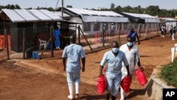 Health workers walk outside the Ebola isolation section of Mubende Regional Referral Hospital, in Mubende, Uganda, Sept. 29, 2022. 