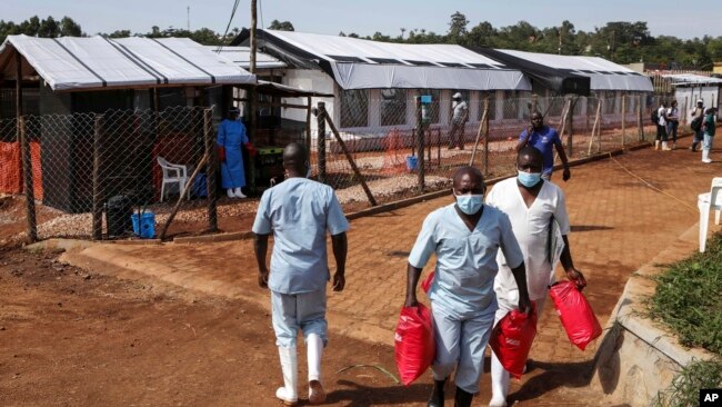 Health workers walk outside the Ebola isolation section of Mubende Regional Referral Hospital, in Mubende, Uganda, Sept. 29, 2022.