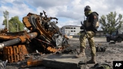 A Ukrainian soldier stands near a damaged Russian tank in Kupyansk in the Kharkiv region, Ukraine, Oct. 4, 2022. 