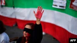 A woman raises her hand with red paint during a demonstration in support of Iranian women on Oct. 4, 2022, in Barcelona following the death of Kurdish Iranian woman Mahsa Amini in Iran.