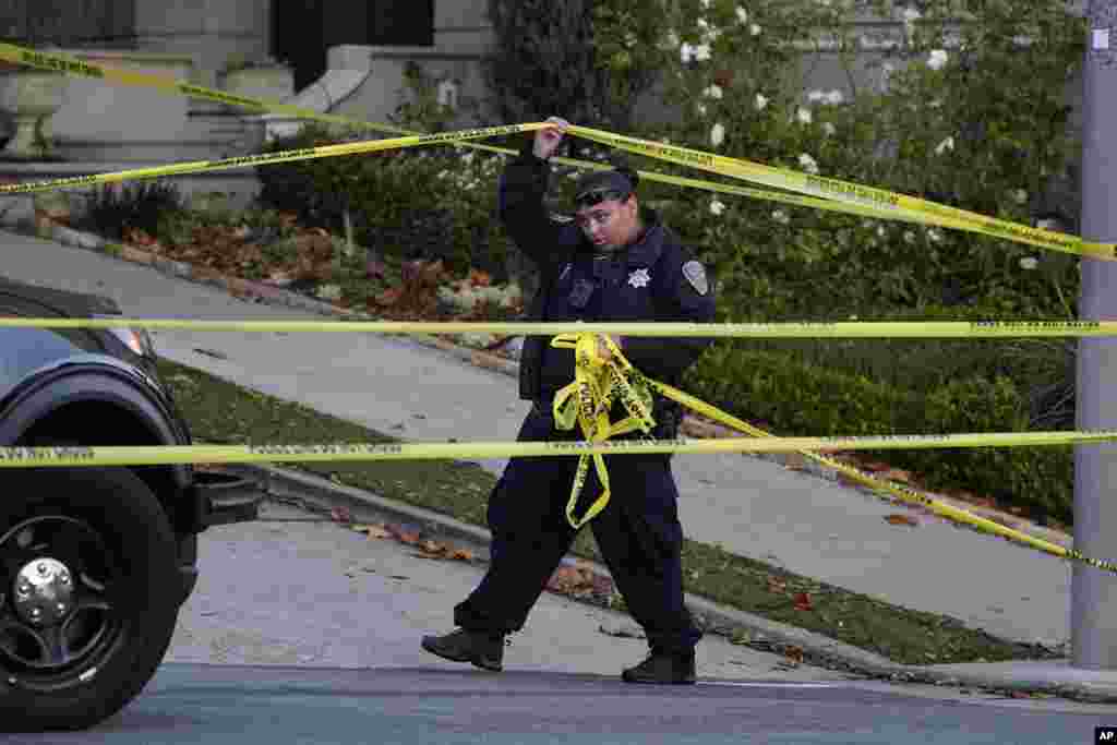 A police officer rolls out more yellow tape on the street below the home of Paul Pelosi, husband of House Speaker Nancy Pelosi in San Francisco. Paul Pelosi was attacked and severely beaten by someone who broke into their home.