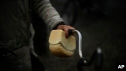 A woman grabs bread as locals receive humanitarian food in Sviatohirsk, Ukraine.