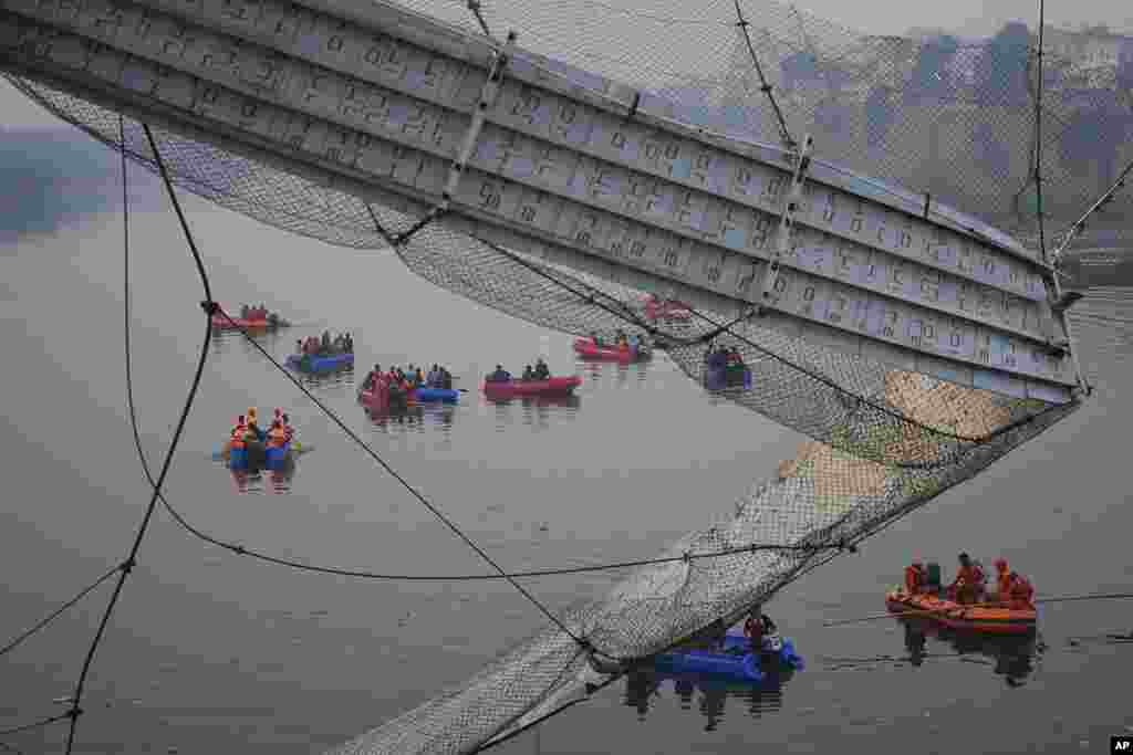 Rescuers on boats search in the Machchu river next to a cable suspension bridge that collapsed in Morbi town of western state Gujarat, India. The century-old cable suspension bridge collapsed into the river Sunday evening, sending hundreds plunging in the water, officials said.