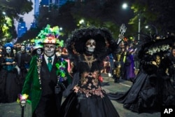 People dressed as Mexico's iconic "Catrinas" march in the Grand Procession of the Catrinas, an early part of Day of the Dead celebrations in Mexico City, Oct. 23, 2022.