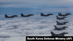 In this photo provided by South Korea Defense Ministry, South Korean Air Force's F15K fighter jets and U.S. Air Force's F-16 fighter jets, fly in formation during a joint drill in an undisclosed location in South Korea, Tuesday, Oct. 4, 2022. The South Ko