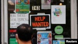 FILE PHOTO: A pedestrian passes a 'Help Wanted' sign in the door of a hardware store in Cambridge, Massachusetts, U.S., July 8, 2022. 