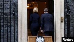 British Prime Minister Liz Truss walks with her husband, Hugh O'Leary, after announcing her resignation, outside Number 10 Downing Street, London, Oct. 20, 2022.