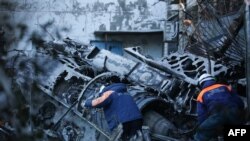 Russian Emergencies personnel remove the wreckage of a Sukhoi Su-34 military jet off its crash site in the courtyard of a residential area in the town of Yeysk in southwestern Russia, Oct. 18, 2022.