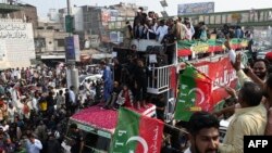 Mantan perdana menteri Pakistan Imran Khan (tengah atas) memberi isyarat kepada para pendukungnya selama pawai anti-pemerintah menuju kota Islamabad, menuntut pemilihan awal, di distrik Muridke, sekitar 29 km dari Lahore, 30 Oktober 2022. (Arif ALI / AFP )