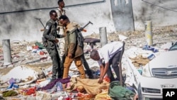 Rescuers and security forces stand by a dead body at the scene of a double car-bomb attack in Mogadishu, Somalia, Oct. 29, 2022. 