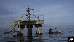 En esta imagen de archivo, un pescador pasa junto a una sonda de petróleo inactiva en el lago Maracaibo, en Venezuela, el 12 de octubre de 2022. (AP Foto/Ariana Cubillos, archivo)