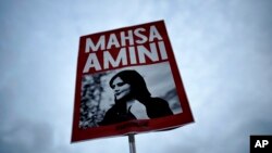 FILE - A woman holds a placard with a picture of Iranian Mahsa Amini during a protest against her death, in Berlin, Germany, Sept. 28, 2022. 