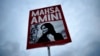 Seorang perempuan mengacungkan poster dengan foto Mahsa Amini dalam demo memprotes kematian Amini usai ditahan polisi moral Iran, di Berlin, Jerman, 28 September 2022. (Foto: Markus Schreiber/AP Photo)