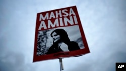 FILE - A woman holds a placard with a picture of Iranian Mahsa Amini during a protest against her death, in Berlin, Germany, Sept. 28, 2022. 