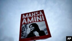 FILE - A woman holds a placard with a picture of Iranian Mahsa Amini during a protest against her death, in Berlin, Germany, Sept. 28, 2022. 