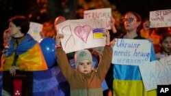 A boy holds a banner as Ukrainians in Romania protest Russian strikes on Ukrainian cities in Bucharest, Monday, Oct. 10, 2022.