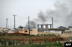FILE - Smoke rises above buildings amid ongoing clashes between rival factions competing for power in northwest Syria, near the village of Jindayris in the Afrin region of Syria's rebel-held northern Aleppo province, Oct. 12, 2022.
