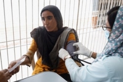 Saima, 23, displaced because of the floods, receives medical assistance while taking refuge in a school in Karachi on September 22, 2022. (Akhtar Soomro/Reuters)