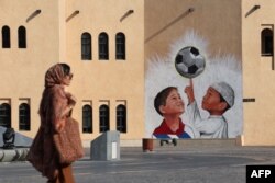 A woman walks past a mural in the Katara Cultural Village, in Qatar's capital Doha, on Oct. 11, 2022.