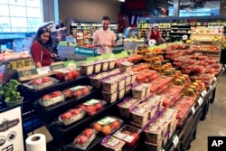 People shop at a grocery store in Glenview, Ill., Monday, July 4, 2022.