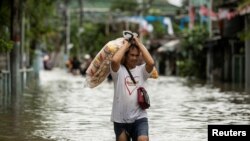 A vendor carries food products as he wades through a flooded street following heavy rains brought by tropical storm Nalgae, in Imus, Cavite province, Philippines, Oct. 30, 2022.