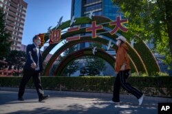 行人走過北京街頭豎立的迎接中共二十大的宣傳牌。 （2022年10月11日）