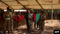 FILE - Burkina Faso servicemen carry a coffin during a funeral in Ouagadougou, Oct. 8, 2022, for 27 soldiers killed as they escorted a convoy in Gaskinde. The ambush, claimed by al-Qaida, has become a symbol of the state's inability to secure countryside areas.