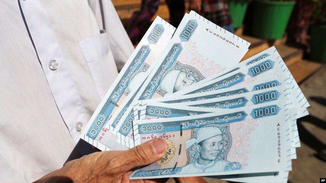 FILE - Seorang pria menunjukkan uang kertas yang dicetak dengan potret Jenderal Aung San, mendiang ayah pemimpin Myanmar Aung San Suu Kyi, di luar Bank Ekonomi Myanmar, 7 Januari 2020, di Yangon, Myanmar. (AP/Thein Zaw, File)