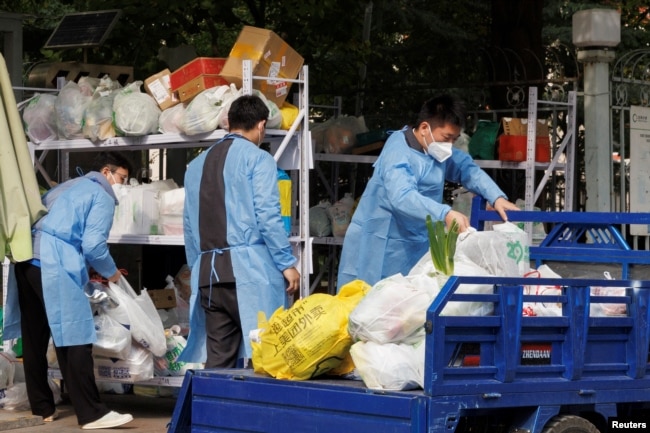 北京一居民区因疫情被封后保安们卸下小区居民购买的食品袋。（2022年10月20日）