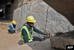 Iraqi workers excavate a rock-carving relief recently found at the Mashki Gate, one of the monumental gates to the ancient Assyrian city of Nineveh, on the outskirts of what is today the northern Iraqi city of Mosul, Oct. 19, 2022.