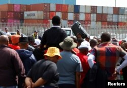 Workers at South Africa's state-owned logistics firm Transnet gather in front of ship containers as they continue on a nationwide strike outside the Port of Cape Town amid talks to end a wage deadlock with the company, in Cape Town, Oct. 11, 2022.