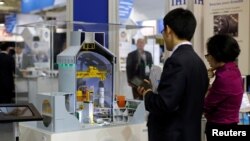 FILE - Visitors look at a nuclear power plant station model by American company Westinghouse at the World Nuclear Exhibition 2014, the trade fair event for the global nuclear energy sector, in Le Bourget, near Paris Oct. 14, 2014.