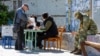 A local resident receives a ballot from polling workers before casting his vote into a mobile ballot box on the third day of a referendum on four Russia-occupied Ukrainian regions joining Russia, in Mariupol, Ukraine, Sept. 25, 2022.