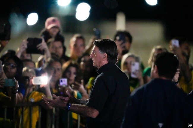 Brazilian President Jair Bolsonaro, who is running for another term, talks to followers after general election polls closed in Brasilia, Brazil, Sunday, Oct. 2, 2022. (AP Photo/Eraldo Peres)