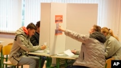 Latvians mark their ballots at a polling station during general elections in Riga, Latvia, Oct. 1, 2022.