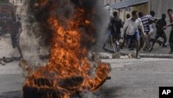 Manifestantes arrojan piedras a la policía durante una protesta por la muerte del periodista Romelo Vilsaint, el 30 de octubre de 2022, en Puerto Príncipe.