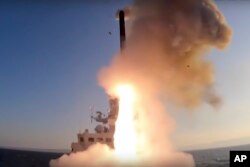 In this handout photo released by Russian Defense Ministry Press Service, Oct. 11, 2022, a Russian warship launches a cruise missile at a target in Ukraine.