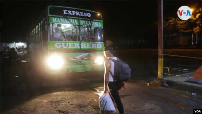 Un nicaragüense aborda un autobús de madrugada con rumbo a la frontera de Honduras para seguir su tránsito a EEUU. Foto VOA