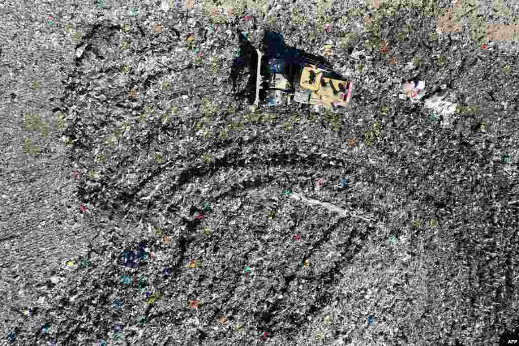 An aerial view shows a digger pushing waste to flatten a hill of rubbish, at a private landfill in Viggianello close to the south western town of Propriano on the French Mediterranean island of Corsica.