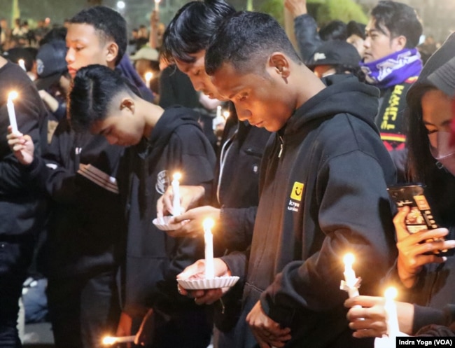 Ribuan pendukung Arema FC yang dikenal sebagai Aremania mendatangi Balai Kota Malang pada Rabu (5/10) malam untuk menggelar acara doa bersama atas insiden Stadion Kanjuruhan pada Sabtu (1/10). (Foto: VOA/Indra Yoga)