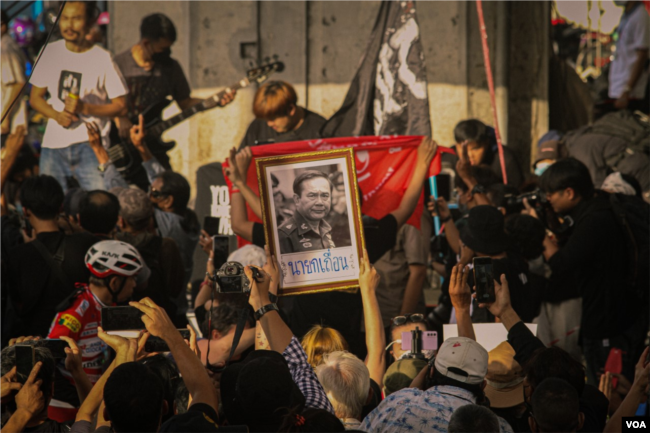 A protester holds up a picture of Thai Prime Minister Prayut Chan-o-Cha during protests beside Victory Monument in Bangkok, Thailand, Oct. 1, 2022, (Tommy Walker/VOA)