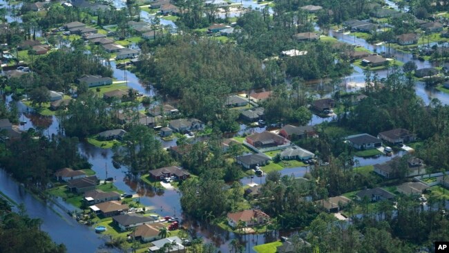 Homes are surrounded by flood waters caused by Hurricane Ian, Thursday, Sept. 29, 2022, in Fort Myers, Fla. Climate change added at least 10 percent more rain to Hurricane Ian, a study prepared immediately after the storm shows. (AP Photo/Marta Lavandier)