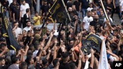 Mourners carry the body of Matin Dababa, draped in the Islamic Jihad flag, at his funeral in the Jenin refugee camp, Oct. 14, 2022. The Palestinian Health Ministry says the Israeli military shot and killed two Palestinians, including Dababa, during a raid into the Jenin camp.