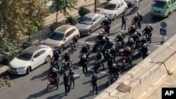 FILE - This image from a video taken by an individual not employed by the AP and obtained outside Iran shows police arriving to disperse a protest to mark 40 days since the death of Mahsa Amini, in Tehran, Oct. 26, 2022.