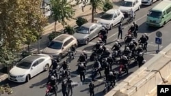 Esta imagen tomada de un video de un individuo no empleado por AP y obtenida fuera de Irán muestra a la policía llegando a una protesta en Teherán, el 26 de octubre de 2022.