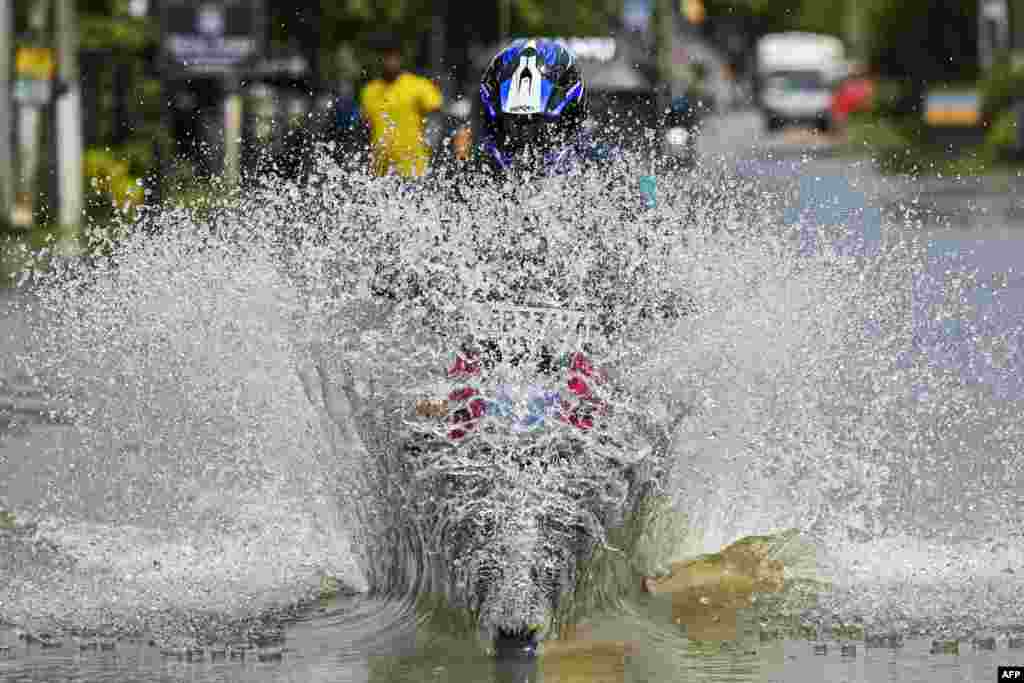 A man rides a motorbike through a flooded street after heavy rains on the outskirts of Colombo, Sri Lanka.